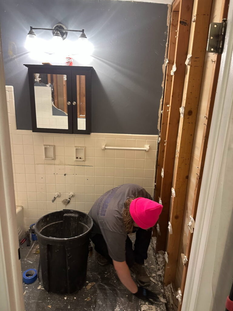 A handyman demolishing the bathroom floor during a renovation project by Urban Restoration, LLC in Indianapolis, IN