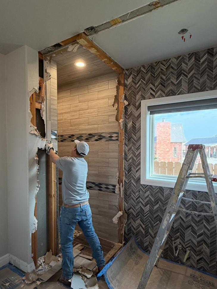 A handyman from Le Roux Homes demolishing a bathroom wall during a renovation project in Enid, OK.