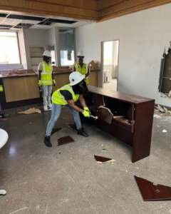 A handyman worker demolishing a wooden cabinet or desk for Ringenberg Construction, LLC in Virginia Beach, VA.