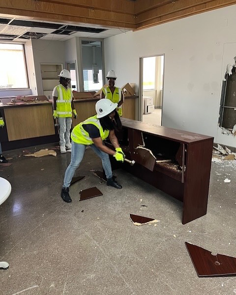 A handyman worker demolishing a wooden cabinet or desk for Ringenberg Construction, LLC in Virginia Beach, VA.