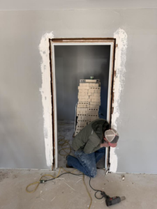 A handyman performing door frame repair and installation for S&B Construction Services in Shreveport, LA.