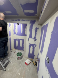A handyman performing drywall finishing work on a bathroom renovation project by Home Improvements by Duane in Racine, WI.