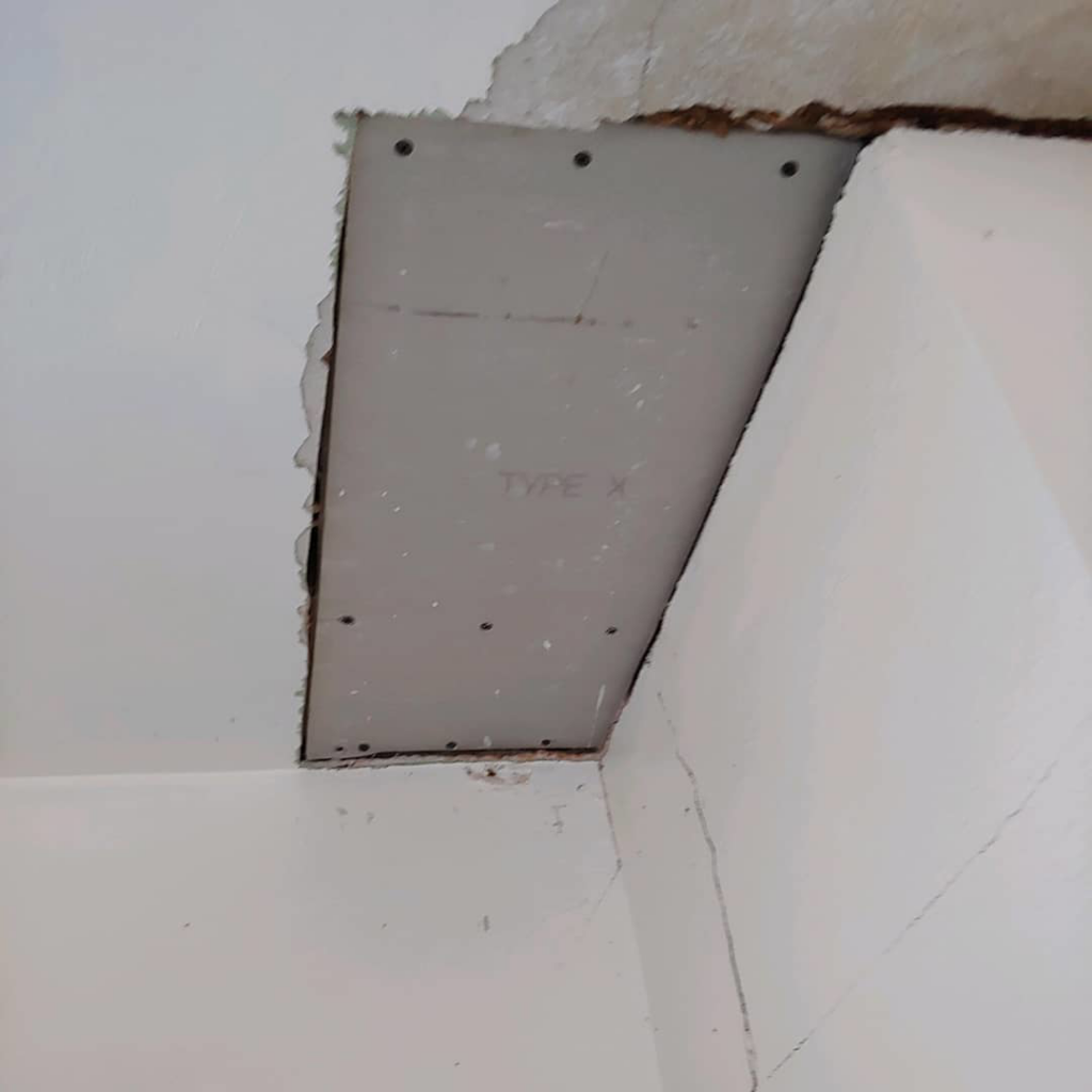 A new drywall patch being installed in a ceiling corner by JPC Plaster & Drywall in Ann Arbor, MI.