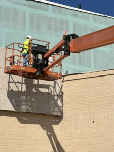 A handyman in a lift performing exterior wall finishing services for CWC Interiors in Tulsa, OK.