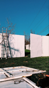 A work site showing a ladder and white panels for a fence or gate installation, performed by Tallgrass fabrication in Edmond, OK.