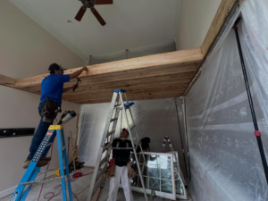 Two handymen working on framing and construction on ladders for Rochester Contracting in Holly Springs, NC.