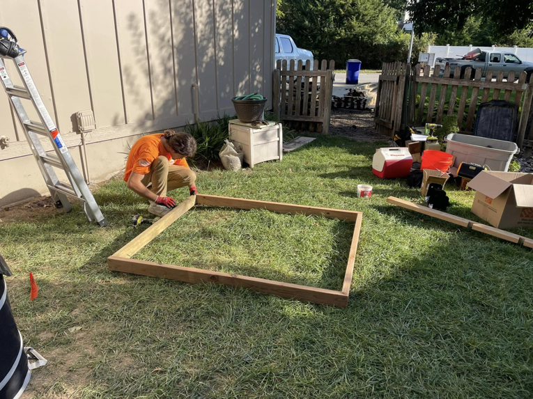 A handyman framing a wooden structure on a lawn for Anderson and Son Services in Olathe, KS