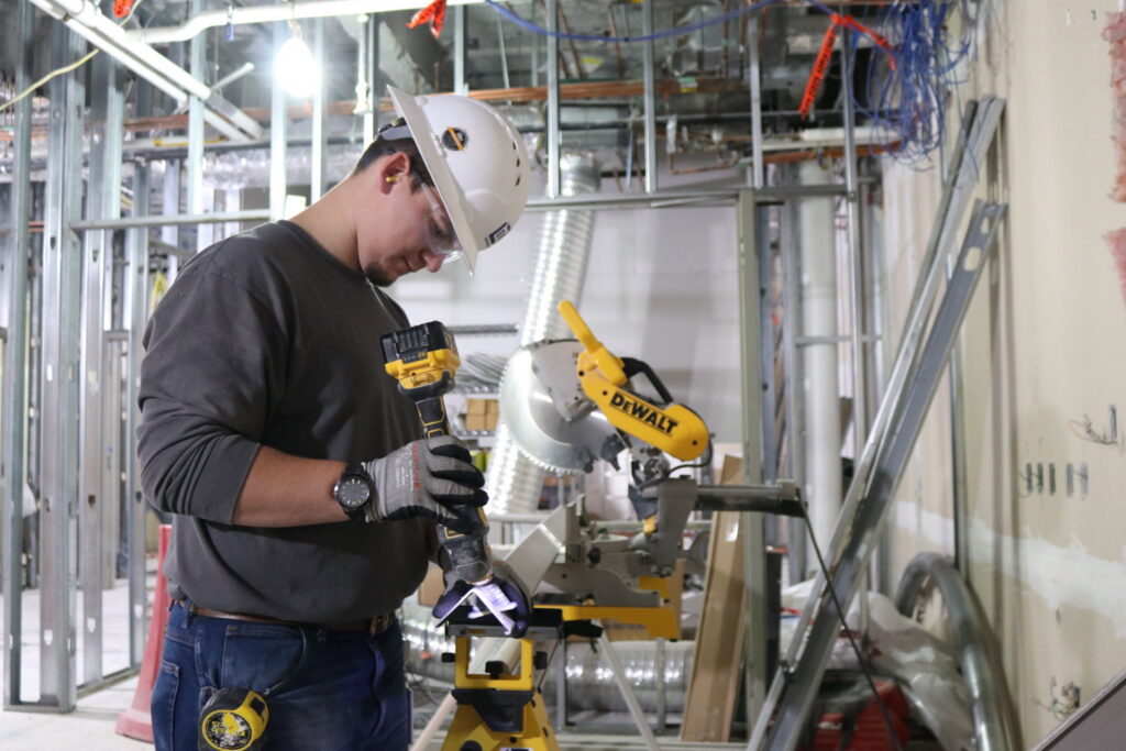 A handyman from EV Construction grinding a metal piece at a construction site in Holland, MI.