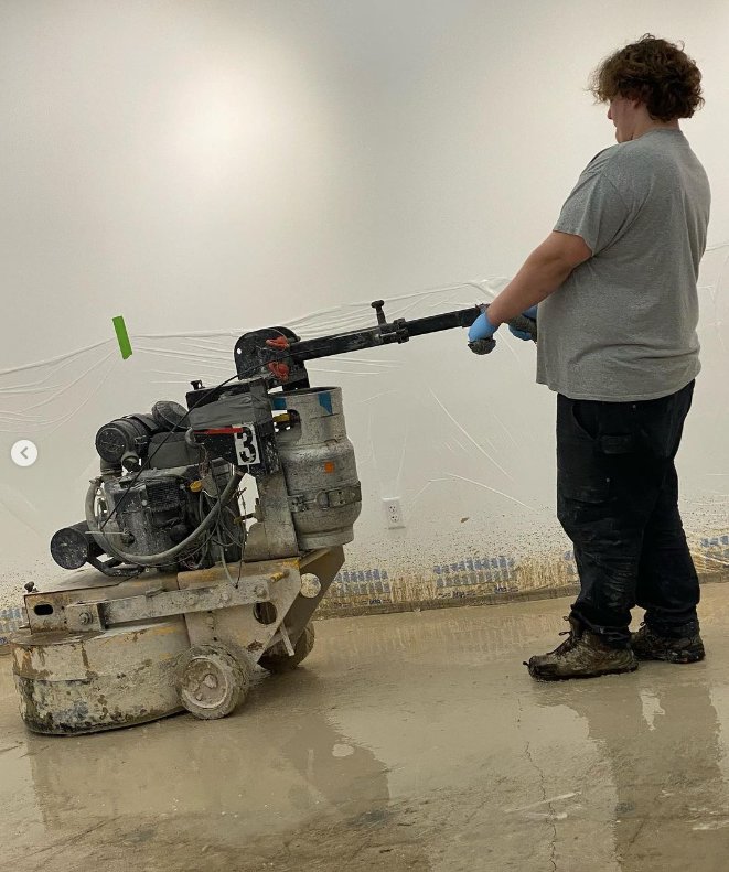 A handyman from ACT Restoration grinding a wet concrete floor as part of a restoration project in Andover, MN.