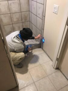 A handyman carefully grouting or sealing bathroom shower tiles, using a specialized tool, by MDJ Handyman in Salt Lake City, UT.
