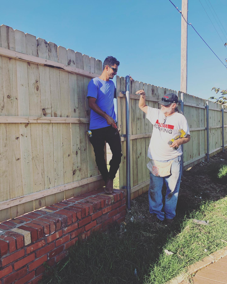 A handyman from Alva Roofing inspecting a newly installed wooden fence in Oklahoma City, OK.