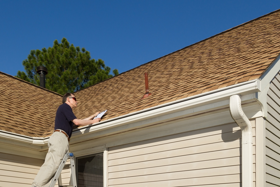 A handyman from A D&D Contracting inspecting a residential roof and gutter in Hallsville, MO.