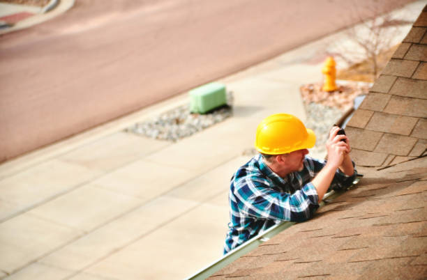 A handyman in a yellow hard hat inspecting a shingle roof for Chris Roofing & Remodeling Inc. in Colorado Springs, CO