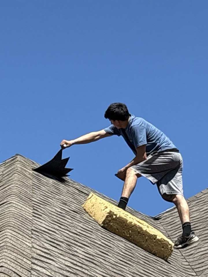 A handyman inspecting or repairing a shingle roof for Hansen Construction Stillwater in Stillwater, OK.