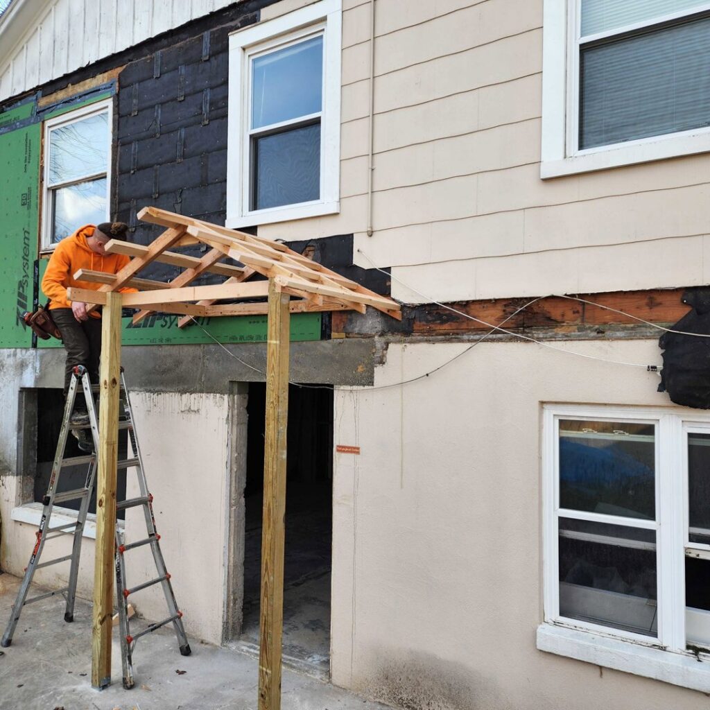 A handyman from Holaway Handyman installing a new awning and performing exterior repair on a house in Fayetteville, AR.