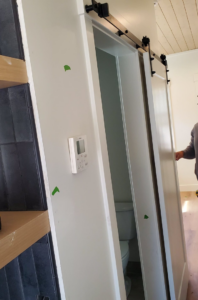 A handyman from Blue Ridge Customs LLC installing a modern barn door in a home in Raleigh, NC.