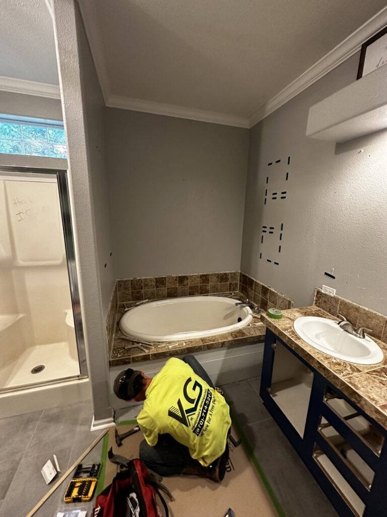 Handyman installing a bathroom vanity and working near a new tub by KG Handyman & Remodeling in Vilonia, AR.