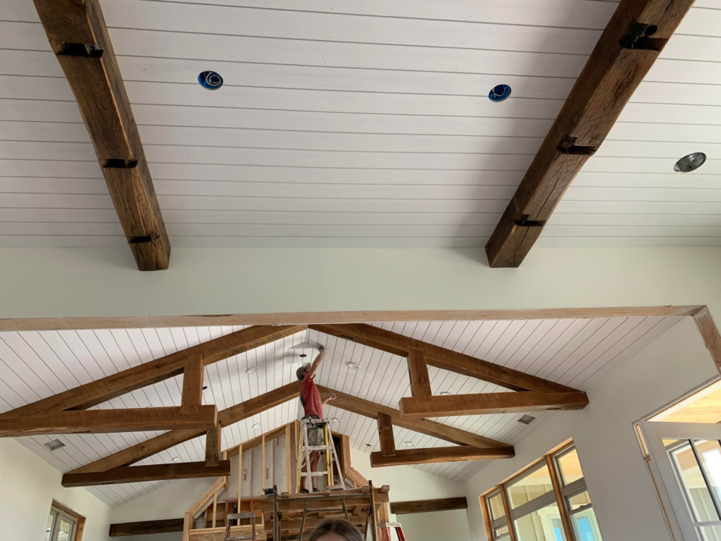 A handyman on a ladder installing a ceiling fixture in a home in Joseph, OR, by Foursquare Homes Inc.