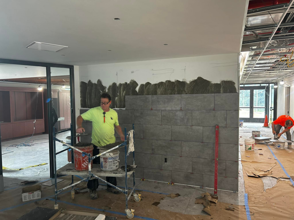 A handyman installing ceramic wall tiles on a construction site for BRB Ceramic Tile & Marble in Metuchen, NJ