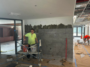 A handyman installing ceramic wall tiles on a construction site for BRB Ceramic Tile & Marble in Metuchen, NJ