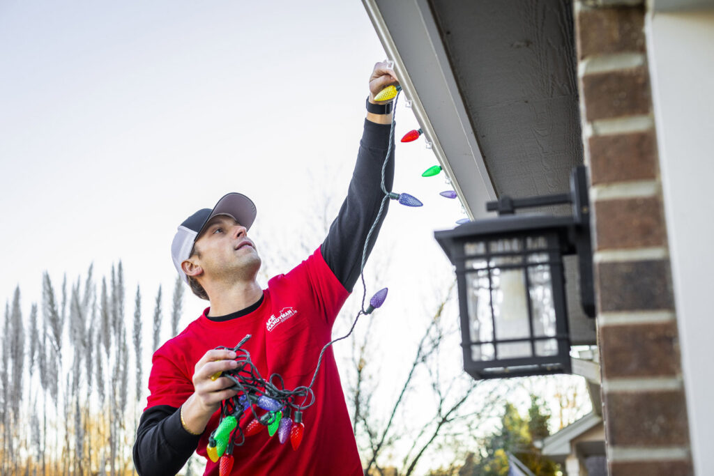 A handyman from Ace Handyman ABQ SF installing Christmas lights on a residential home in Albuquerque, NM