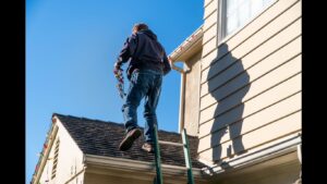 A handyman from Lights Made Easy of Charleston, SC, safely installing Christmas lights on a house roofline using a ladder