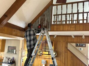 A handyman on a ladder installing decorative corrugated metal paneling on a wall in Olathe, KS, provided by Mr. Handyman of Olathe, Gardner.