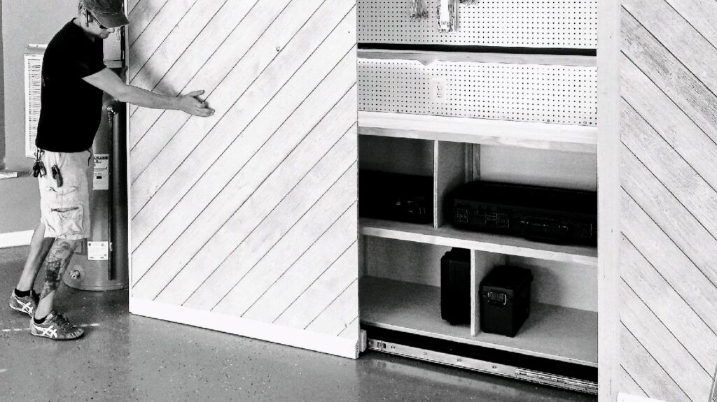 A handyman installing a custom sliding wall and storage system in a garage, a service provided by Huff Consolidated Enterprises LLC in Clarksville, TN.
