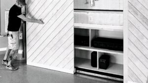 A handyman installing a custom sliding wall and storage system in a garage, a service provided by Huff Consolidated Enterprises LLC in Clarksville, TN.