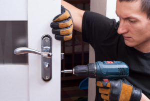 A handyman installing a new door handle and lock with a drill for Door Tech of Nashville, Inc. in Nashville, TN.