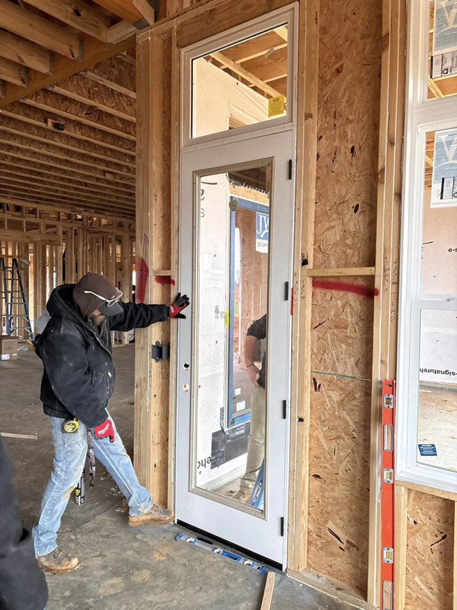 A handyman installing a white-framed door in a new construction project by Harwell's Handyman & HVAC Services in Dickson, TN.