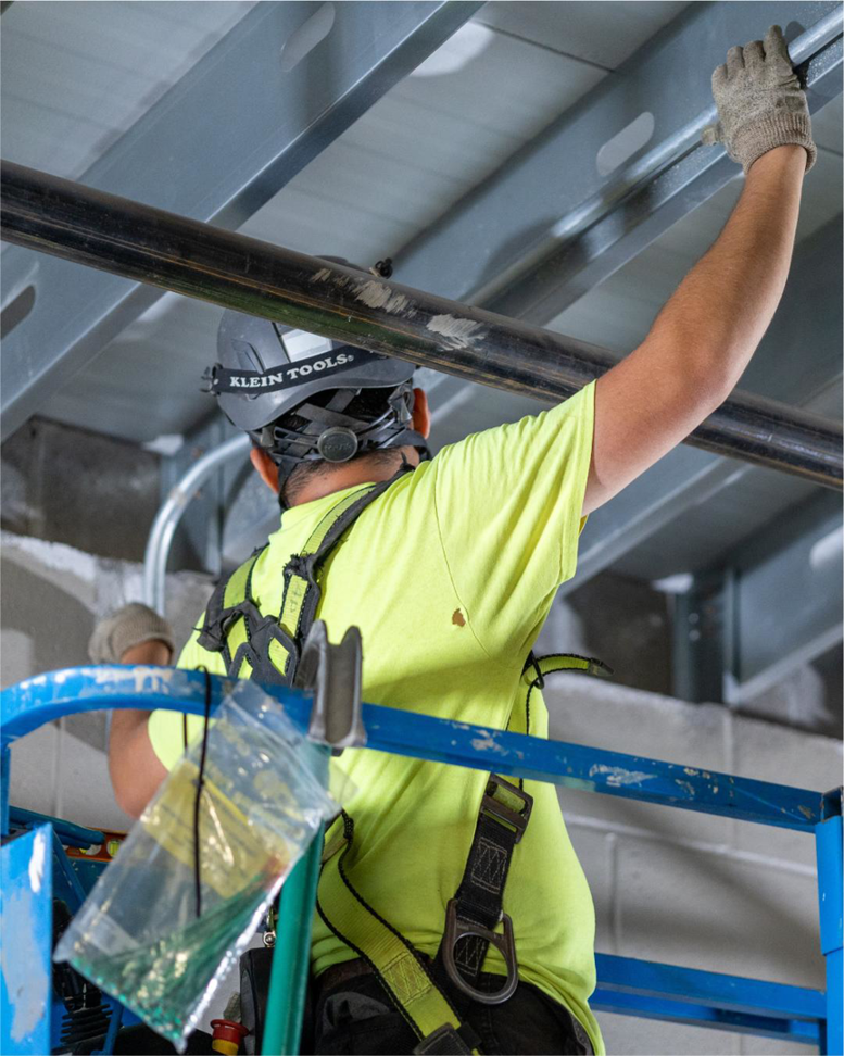A handyman from M&L Electrical, Inc. installing electrical conduit from a scissor lift in Bowling Green, KY.