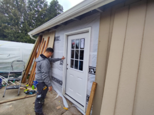 A handyman installing a new exterior door on a building, showcasing services from JJU Property Maintenance, LLC in Salem, OR.