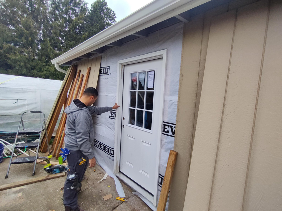 A handyman installing a new exterior door on a building, showcasing services from JJU Property Maintenance, LLC in Salem, OR.
