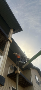 A handyman installing exterior siding from a lift on a building project by New Life Custom Carpentry in Livonia, MI.