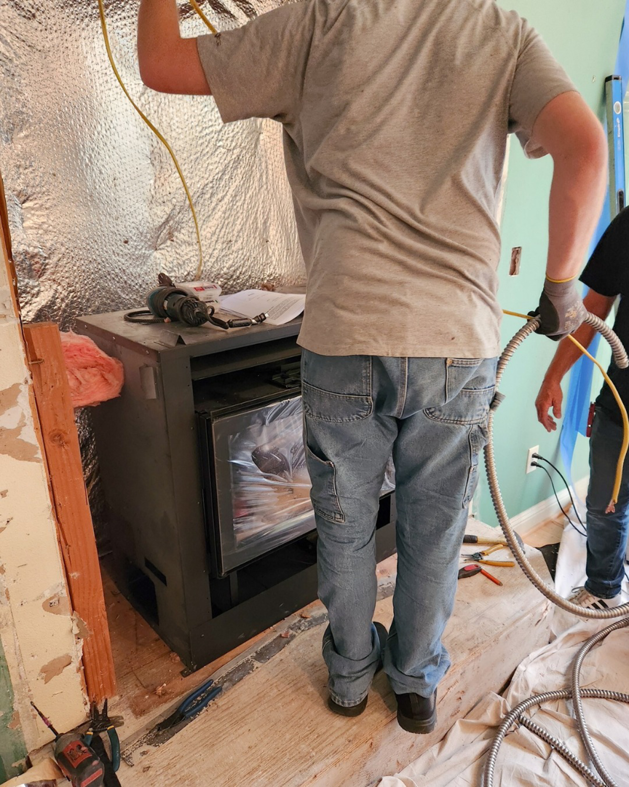 A handyman installing a new fireplace insert and wiring at a job site for Portland Fireplace and Chimney Inc. in Portland, OR.