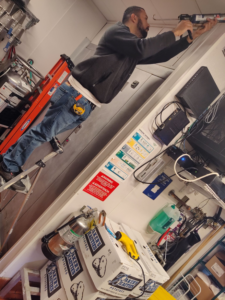 A handyman on a ladder installing or repairing a fixture in a commercial space, provided by JJU Property Maintenance, LLC in Salem, OR.