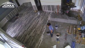A handyman from JOMA Construction installing new floor tiles during a renovation project in Athens, GA.