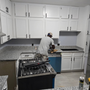 A handyman installing a kitchen appliance or working on plumbing for Paschal Construction LLC in Memphis, TN.