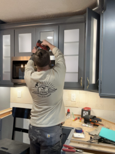 A handyman from Affordable Home Solutions installing kitchen cabinets and appliances in Springfield, PA.