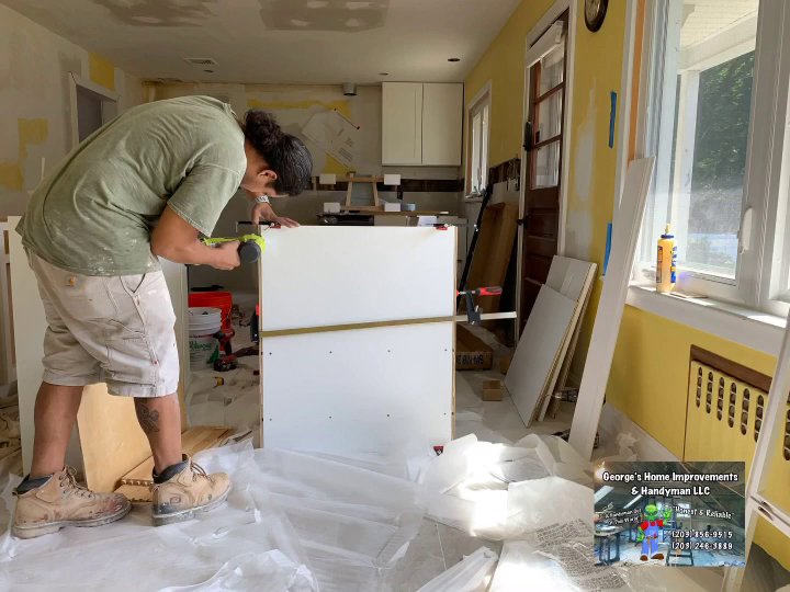 Handyman installing kitchen cabinets during a home improvement project by George's Home Improvement & Handyman LLC in Norwalk, CT.