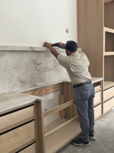 A handyman from Javier's Countertops installing a kitchen countertop or backsplash with a drill in Springdale, AR