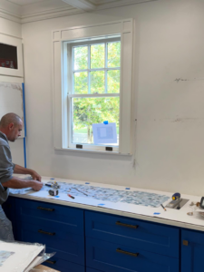 A handyman from Ayres Endeavors, LLC installing intricate mosaic tiles on a kitchen wall in New Orleans, LA.