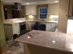 A handyman installing kitchen sink plumbing during a renovation project by Ironside Home Improvements, LLC in Madison, WI.