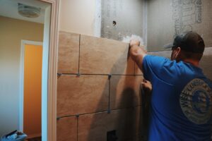 A handyman installing large format tiles on a shower wall for a renovation by Home Changes in Knoxville, TN