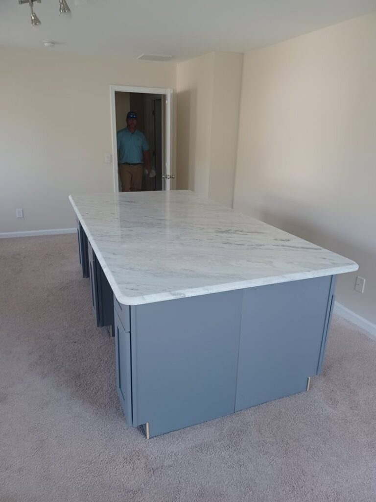 A handyman from Counter Fitters installing a white marble kitchen island countertop in a home in Savannah, GA