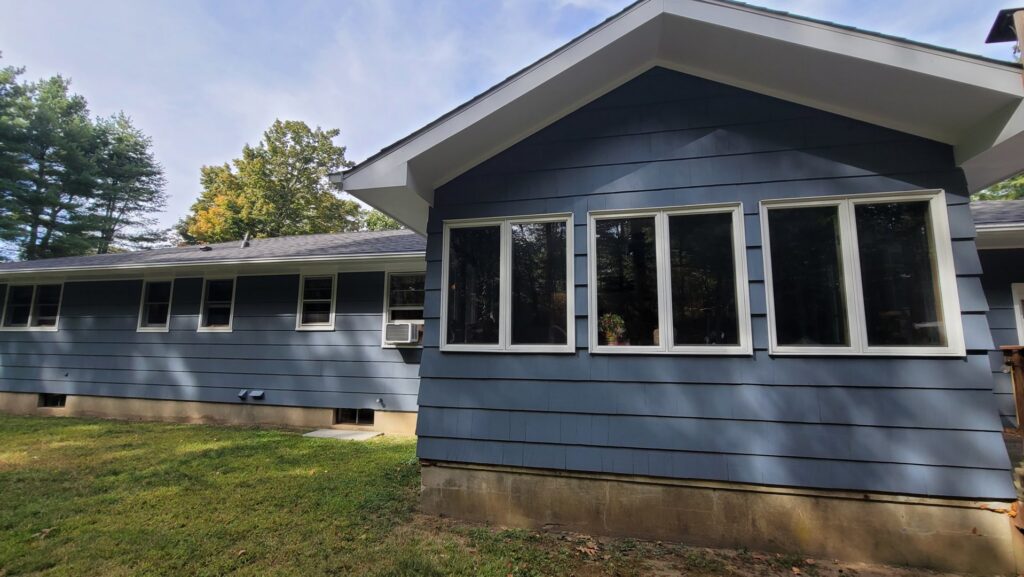 A handyman installing a new gutter system with a power drill for Casanova Remodeling in Plymouth, CT.