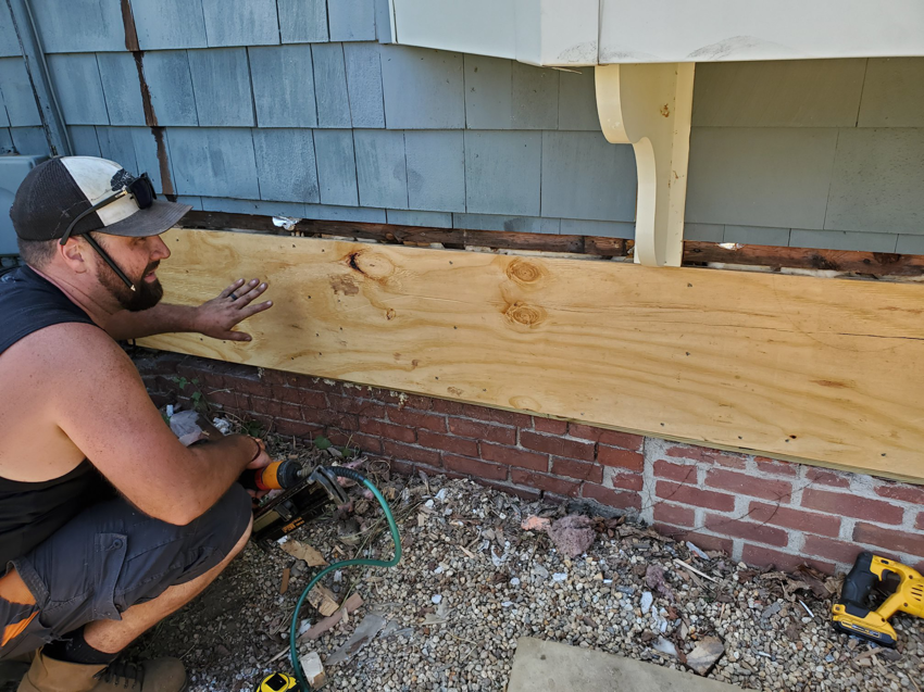 A handyman installing a new wooden sill on a house foundation for Richard C. Michalak in Worcester, MA.