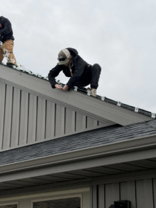 A handyman carefully installing outdoor lights on the roof of a house, a service offered by JP Handyman Wyo in Sheridan, WY