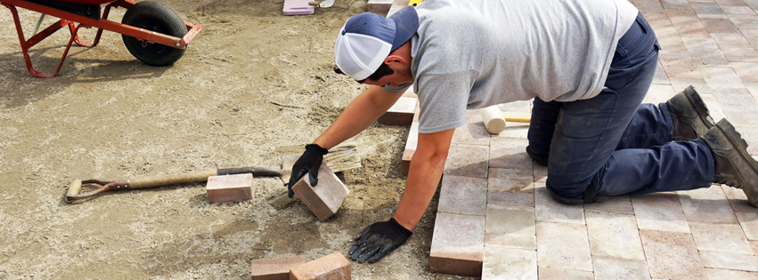 A handyman installing patio pavers for a new walkway or patio at Blue Marlin Masonry Services in Toms River, NJ.